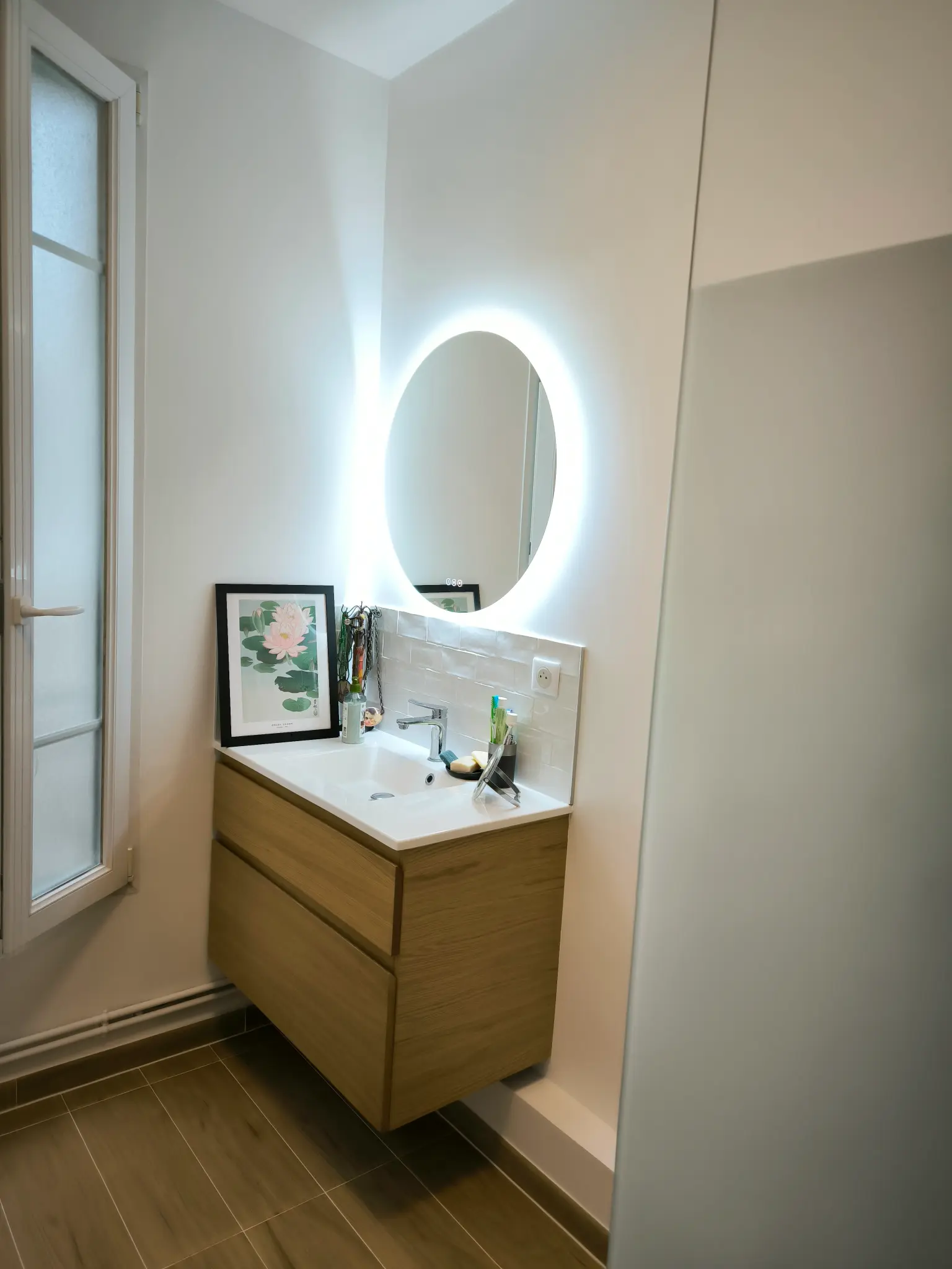 Meuble vasque en bois avec miroir rond éclairé dans une salle d’eau